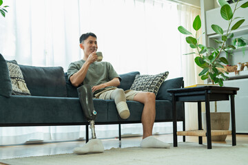 ソファでコーヒーを飲む義足の男性