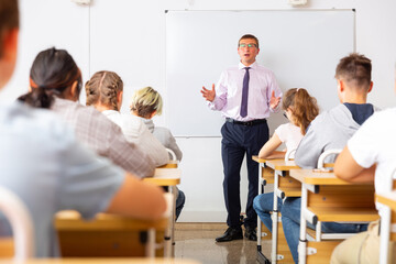 Adult teacher is giving lecture for students in the class