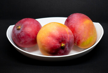 Bol de manga venezolana. Tres mangos. Mango en bol fondo negro. Manga fruta venezolana
