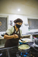 Vertical shot of a Hispanic woman cooking chicken with mushroom sauce