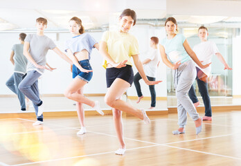 Fototapeta na wymiar Teenagers in dance hall studying new movements, smiling and having fun