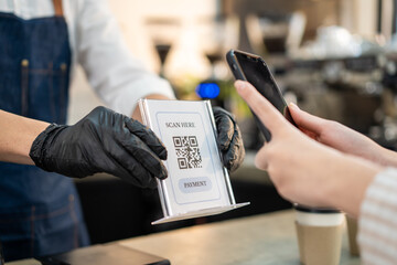 Close-up shot of waiter handing QR code to customer scan for payment.