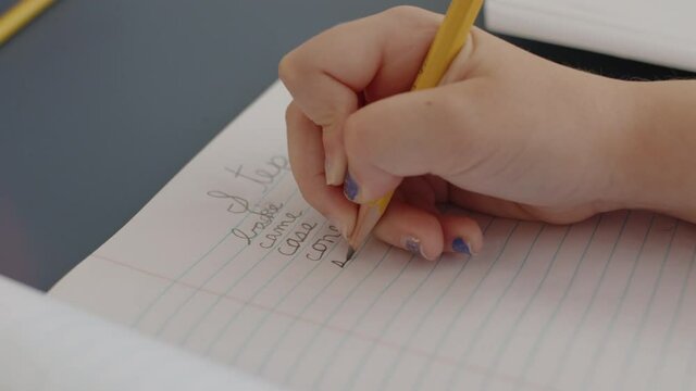 Handheld shot of girl writing cursive words while being homeschooled