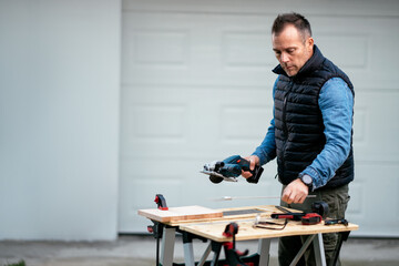 a man working with equipment on a wooden table in his backyard