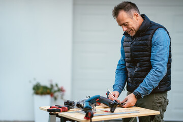 a man working with equipment on a wooden table in his backyard