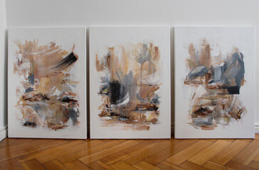 Art collection. Three contemporary abstract paintings on the wooden floor of the art studio....