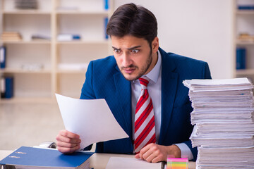 Young businessman employee unhappy with excessive work in the office