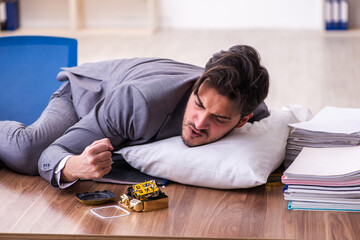 Obraz premium Young male employee in oversleeping concept
