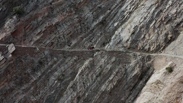 Red Old 4x4 Jeep Driving On Steep Cliffside Towards Fairy Meadows Road In Pakistan. - Aerial Shot