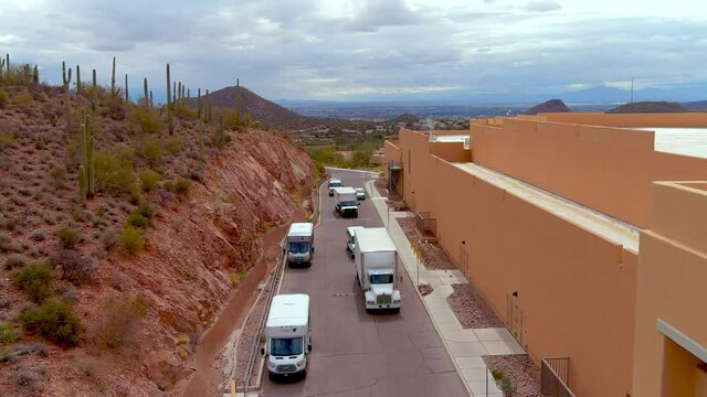 Drone shot of trucks pulling in behind a hotel or large building