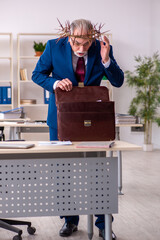Old male employee wearing prickly wreath on head