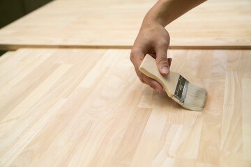 Applying protective painting varnish by hand on a wooden texture, diy and repair house equipment...