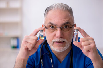 Old male doctor in vaccination concept
