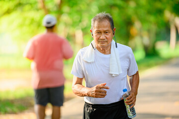 Asian elderly man or senior runner Smile happily In jogging Outdoor and walking workouts in the park