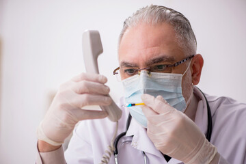 Old male doctor in vaccination concept