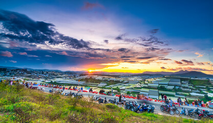 Sunset landscape in agricultural greenhouse valley attracts tourists to roadside coffee for sightseeing, relaxing at the end of day in Da Lat plateau, Vietnam
