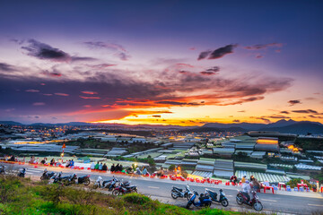 Sunset landscape in agricultural greenhouse valley attracts tourists to roadside coffee for sightseeing, relaxing at the end of day in Da Lat plateau, Vietnam