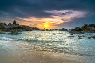 Fototapeta premium Beautiful sunrise on the beach below the waves lapping at the shore of the soft great to welcome the peaceful new day