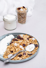 Granola with chia seeds, coconut, dry berries and yogurt in bowls on grey background, copy space. Concept of healthy breakfast menu