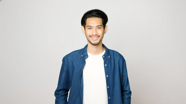 Portrait Of Asia Man Smiling And Looking At Camera While Standing Over Isolated Grey Background