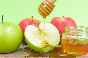 Jewish holiday, Apple Rosh Hashanah, the photo have honey in jar and drop honey on green apples on wooden with green background