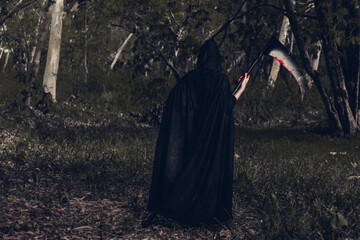 Back woman horror ghost holding reaper in forest, halloween concept