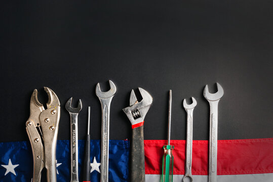 Labor day concept, Top view flat lay of different kinds wrenches with American flag on black. First Monday in September, creation of labor movement and dedicated to social of the American worker