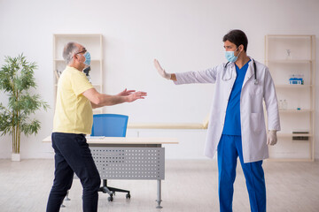 Fototapeta premium Old male patient visting young male doctor in social distancing