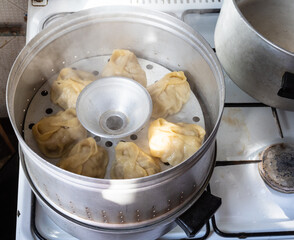 homemade manti are cooking in aluminum steamer - obrazy, fototapety, plakaty
