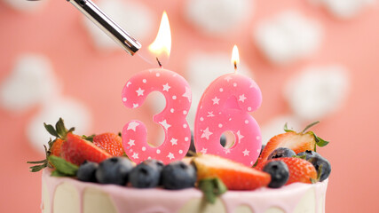 Birthday cake number 36, pink candle on beautiful cake with berries and lighter with fire against...