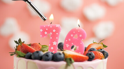 Birthday cake number 76, pink candle on beautiful cake with berries and lighter with fire against...