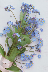 bouquet of forget-me-not flowers on white wooden background