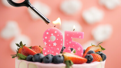Birthday cake number 95, pink candle on beautiful cake with berries and lighter with fire against...