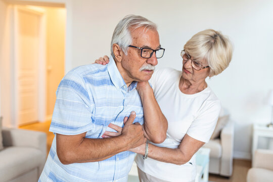 Senior man with neck pain and concerned elderly woman at home