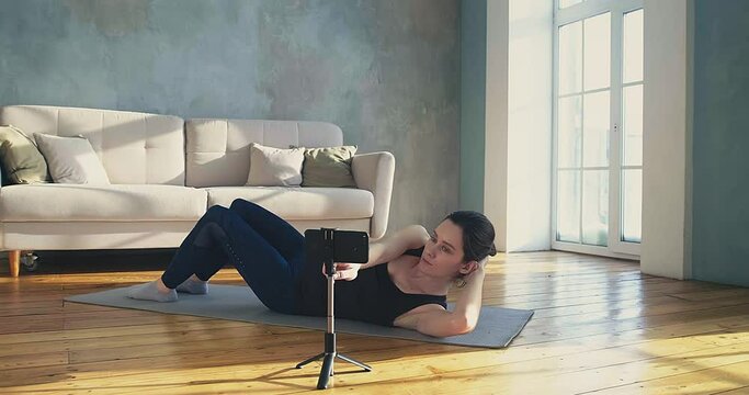 Woman blogger switches on camera to shoot crunches in room