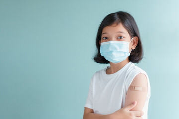 Asian little girl wearing face mask vaccinated Showing arm bandage to protect COVID-19 spread on...