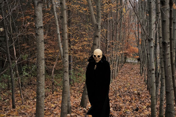 Halloween and horror concept.death suit.skull halloween costume. Autumn traditional masquerade and carnival. Death in the autumn forest. Skeleton costume