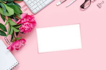 Laptop, accessories and bouquet of beautiful peonies with glasses and headphones on pink background. Flat lay of working place.