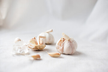 Close-up of garlic on a white tablecloth. Home plant growing, cooking and spices. Sunlight and trending hard shadows. High quality photo
