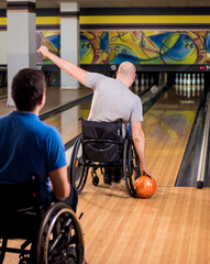 Two young disabled men in wheelchairs playing bowling in the club