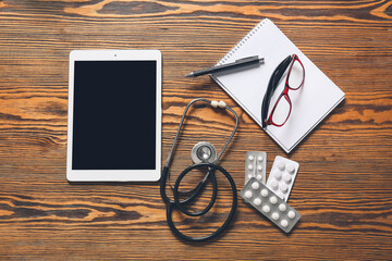 Composition with modern stethoscope and tablet computer on wooden background