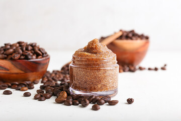 Jar with body scrub and coffee beans on light background
