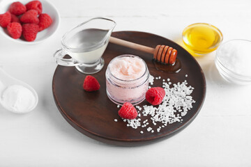 Jar of raspberry body scrub and ingredients on light background