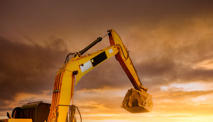 Backhoe working by digging soil at construction site. Closeup hydraulic arm and bucket of backhoe...