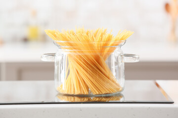 Stylish cooking pot with pasta on stove in kitchen