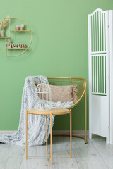 Fototapeta na wymiar Modern armchair with table and folding screen near color wall