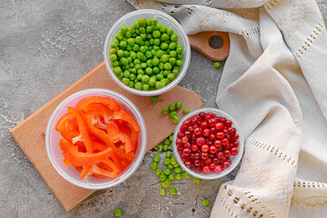 Plastic containers with vegetables on grey background