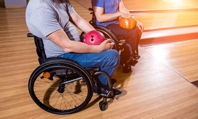 Two young disabled men in wheelchairs playing bowling in the club