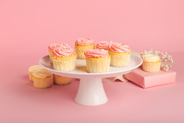 Dessert stand with tasty cupcakes on color background