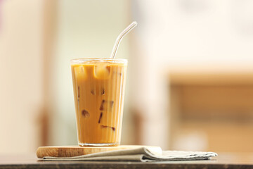 Glass of tasty iced coffee on table in room, closeup